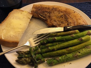 dinner plate with pork chops, roast asparagus, fresh bread