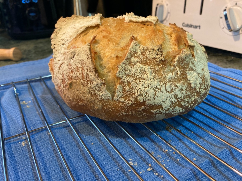 fresh load of bread cooling on a wire rack on top of a blue dish towel